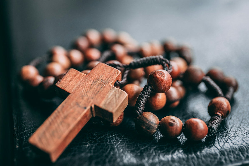 Placeholder photograph of brown wooden rosary beads and a cross. Photo by James Coleman on Unsplash; not an actual Blessed By Mary product.